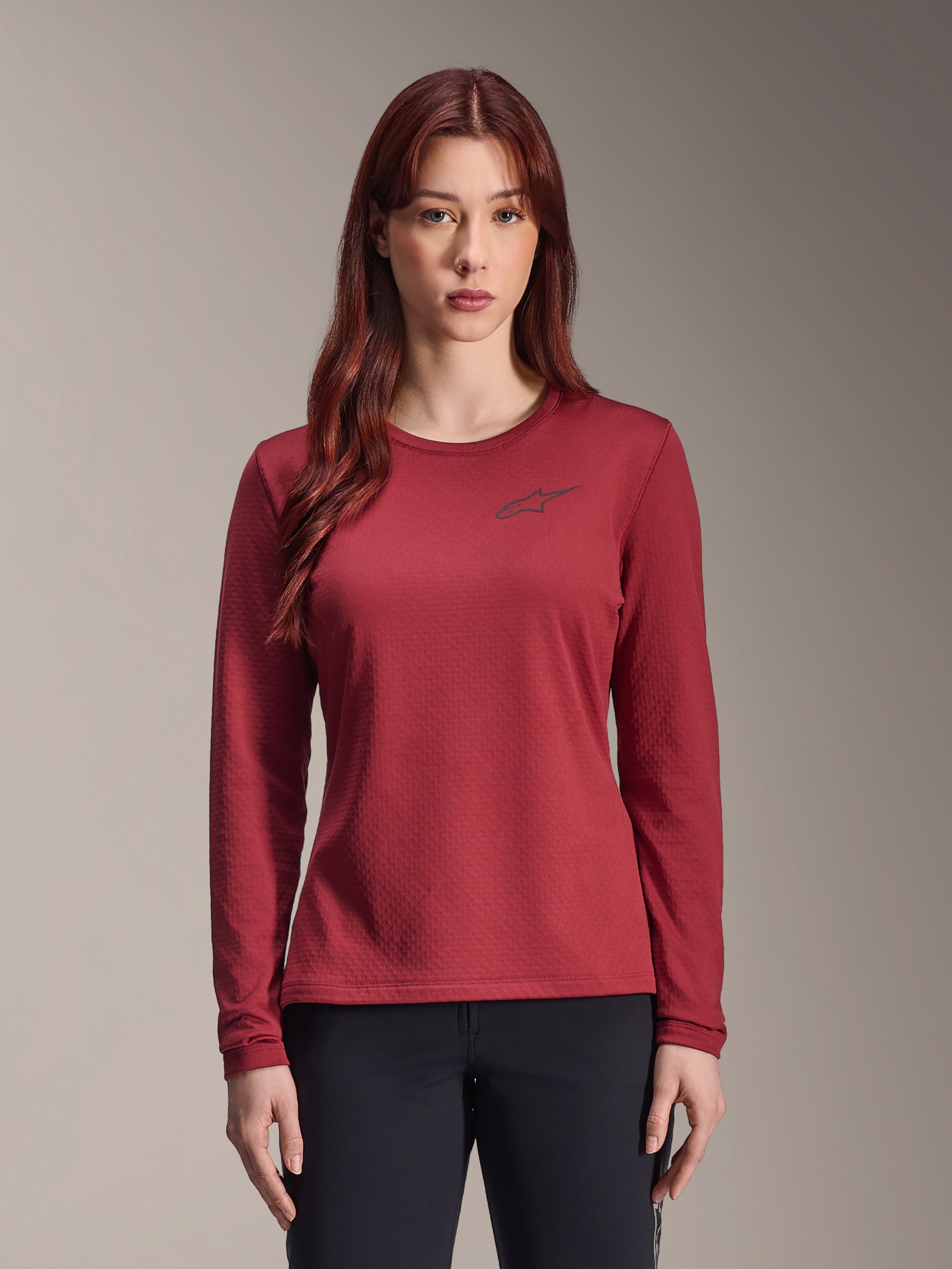 Alpinestars Stella A-Dura Thermal Jersey, maglia MTB a maniche lunghe da donna, bordeaux, tessuto termico testurizzato, girocollo con un piccolo logo Alpinestars nero sul petto, indossata da una modella.