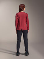 Donna che indossa la maglia termica Alpinestars Stella A-Dura, bordeaux, vista posteriore, maglia da ciclismo isolante a maniche lunghe con coda posteriore allungata, abbinata a pantaloni neri e scarpe da ciclismo nere, abbigliamento da mountain bike.