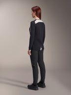 Ciclista con pantaloni Alpinestars Stella A-Dura da donna e maglia Stella A-Dura Elite, nero, vista posteriore con pannelli in rete bianca sulle spalle della maglia a maniche lunghe, pantaloni tecnici slim-fit, abbigliamento coordinato ad alte prestazioni per mountain bike.