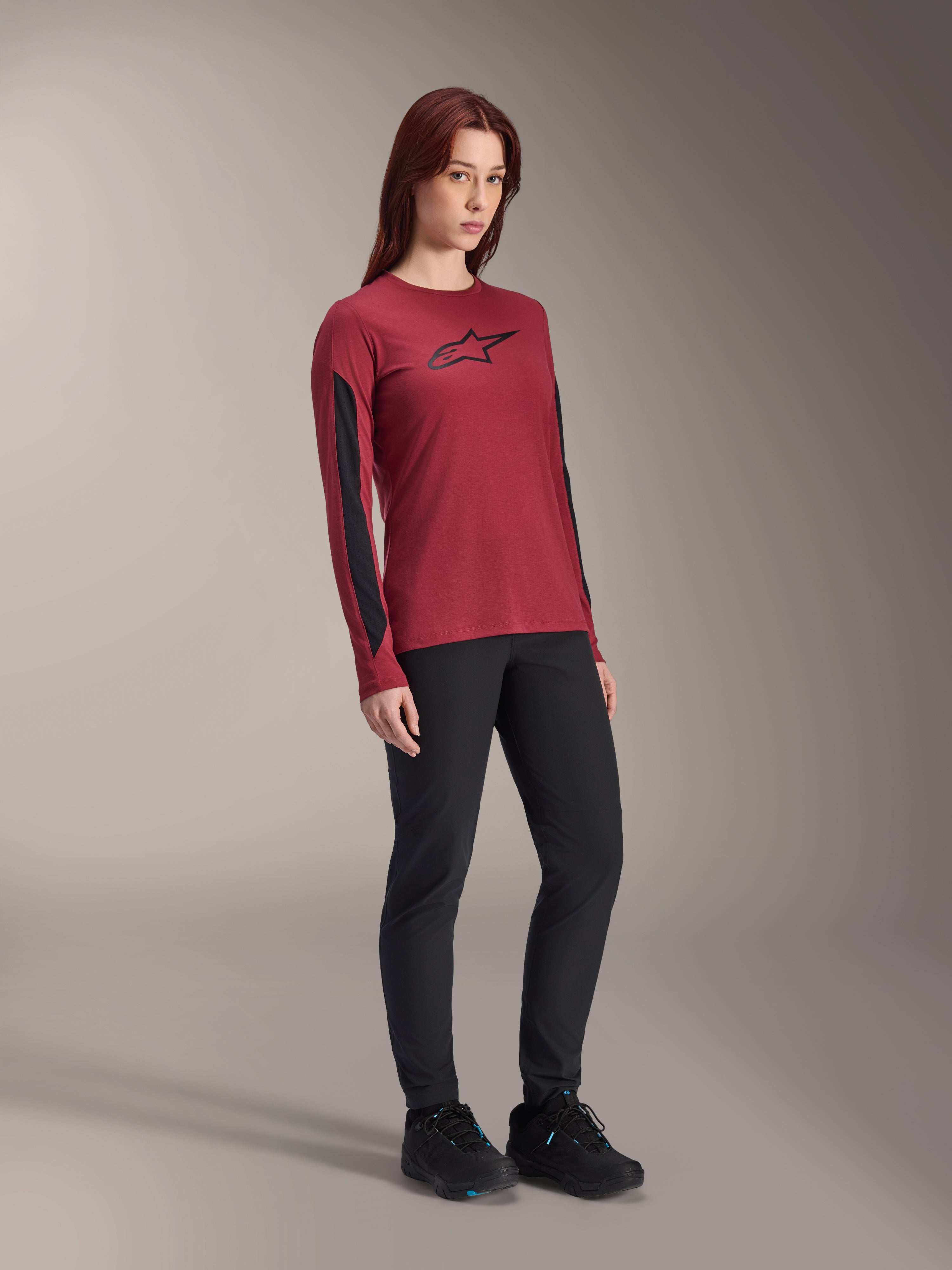Maglia a maniche lunghe Alpinestars Stella A-Dura Dri Astar da donna, rosso bordeaux con logo nero sul petto e pannelli in mesh neri sulle maniche, indossata con pantaloni tecnici neri e scarpe da ciclismo nere, abbigliamento da mountain bike ad alte prestazioni per donna