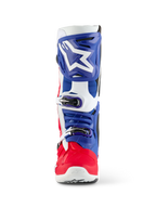 Stivale Alpinestars Limited Edition Fortitude Tech 10, stivale da motocross, rosso acceso, bianco e blu, vista frontale con grande logo a stella bianco sulla placca tibiale blu, sistema di chiusura a tripla fibbia e scocca del piede rosso vibrante, progettato per prestazioni off-road d'élite