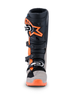 Stivali Alpinestars Tech 7 Enduro 2026, stivali da motocross ed enduro, nero, grigio caldo e arancione fluo, vista frontale con grande logo a stella arancione sullo stinco, sistema di chiusura a fibbie multiple e pannelli protettivi robusti per prestazioni off-road.