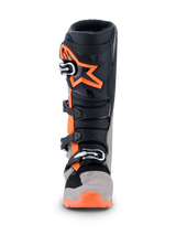 Stivali Alpinestars Tech 7 Enduro 2026, stivali da motocross ed enduro, nero, grigio caldo e arancione fluo, vista frontale con grande logo a stella arancione sullo stinco, sistema di chiusura a fibbie multiple e pannelli protettivi robusti per prestazioni off-road.