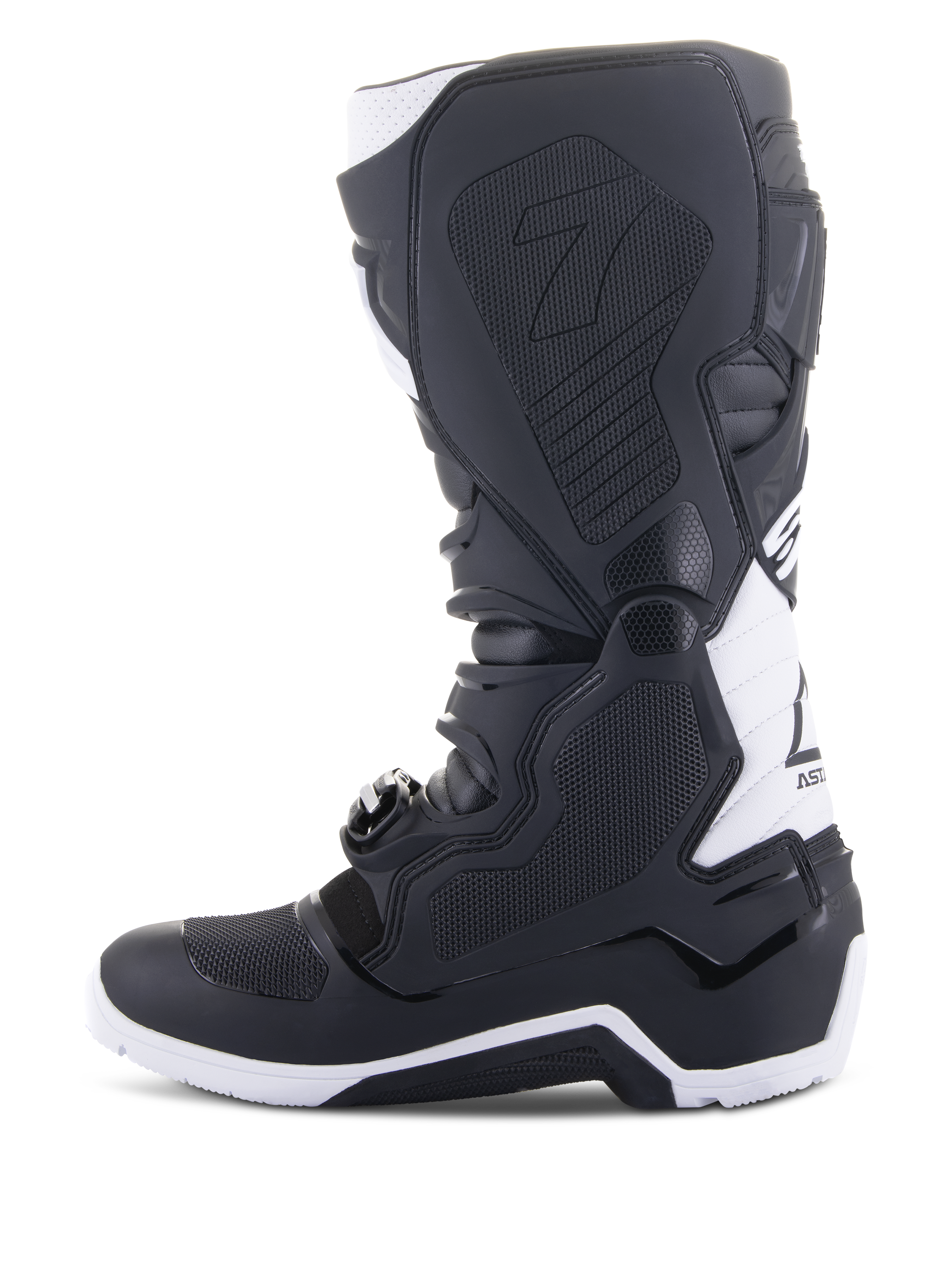 Stivali Alpinestars Tech 7 Enduro Drystar®, stivali da moto enduro, nero e bianco, vista laterale mediale con pannelli grip con trama a nido d'ape, costruzione in TPU e accenti bianchi sul tallone e sulla parte superiore del polpaccio, calzatura professionale da fuoristrada