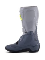 Stivali Alpinestars Tech 3, stivali da motocross, grigio scuro, grigio chiaro e nero, vista laterale con parte superiore grigio chiaro e sezioni inferiori grigio scuro, accenti gialli sulle fibbie, piastre protettive in TPU e suola nera resistente.