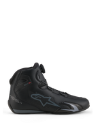 Scarpe Alpinestars Celer, scarpe da moto, nero e grigio scuro, vista laterale di profilo che mostra la rotella del sistema di chiusura Rotor sulla linguetta, tomaia in microfibra tecnica con logo Alpinestars grigio, profilo sportivo e da corsa aerodinamico