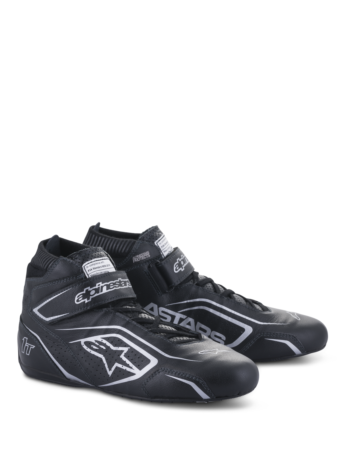 Alpinestars Tech-1 T V3 Shoes FIA, scarpe da auto racing, nero e argento, realizzazione in pelle bovina con loghi e branding Alpinestars argento, vista laterale angolata con chiusura a strappo e lacci