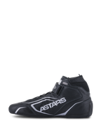 Alpinestars Tech-1 T V3 Shoes FIA, scarpe da auto racing, nero e argento, vista laterale di profilo, costruzione interamente in pelle bovina con marchio ASTARS argento, cinturino a strappo regolabile e colletto ignifugo elastico.