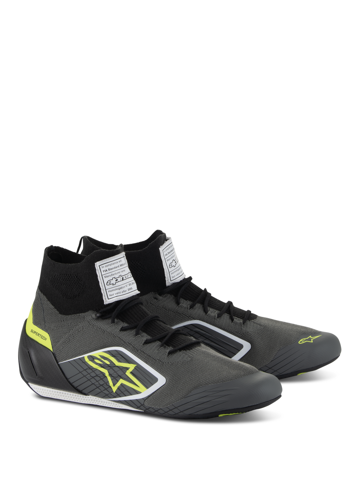 Scarpe Alpinestars Supertech, calzature da auto racing, grigio freddo e nero con accenti giallo fluo, caratterizzate da tomaia in maglia aramidica, tallone in fibra di carbonio ed etichette di certificazione FIA bianche sulla linguetta, design professionale da motorsport