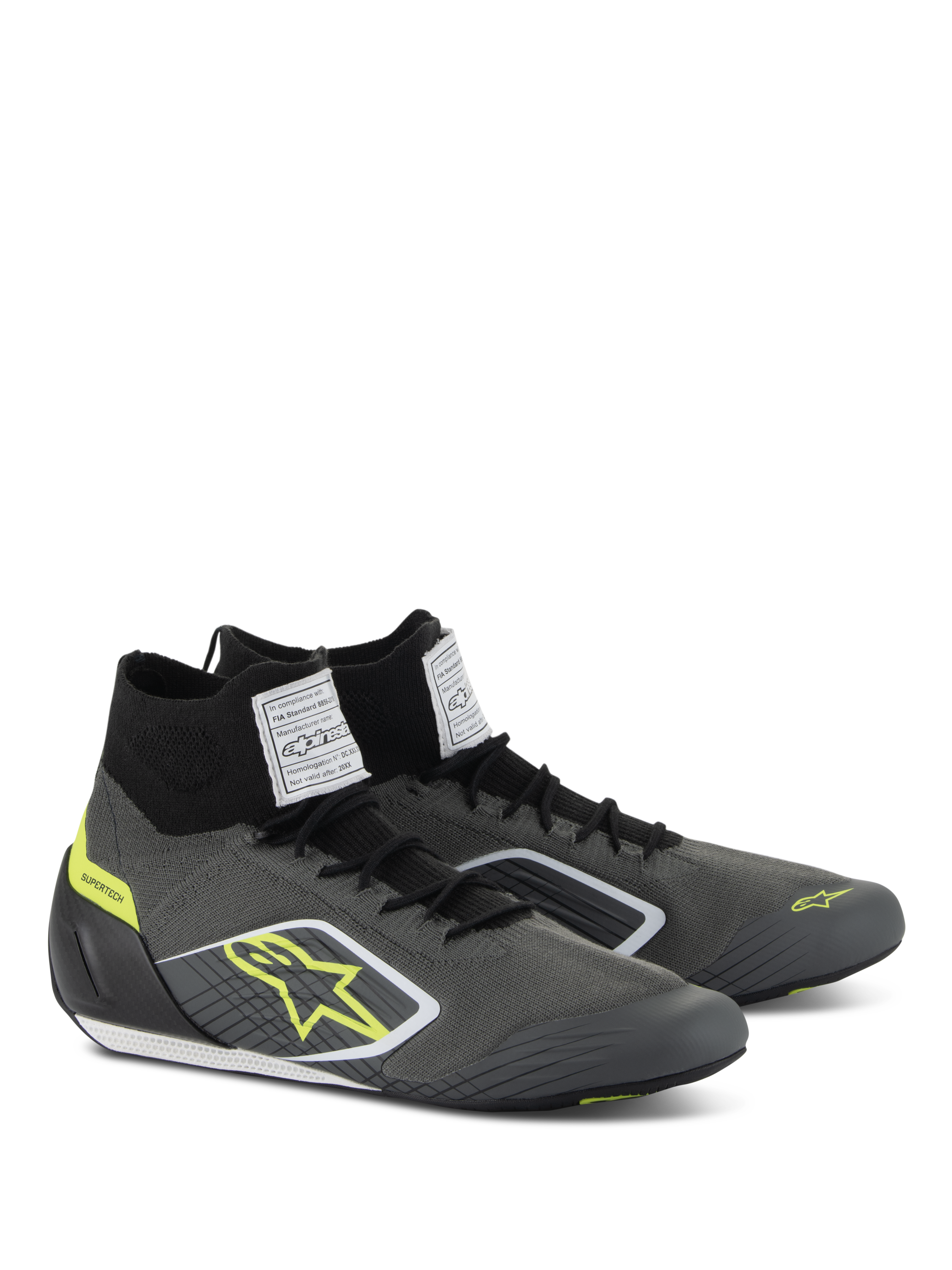 Scarpe Alpinestars Supertech, calzature da auto racing, grigio freddo e nero con accenti giallo fluo, caratterizzate da tomaia in maglia aramidica, tallone in fibra di carbonio ed etichette di certificazione FIA bianche sulla linguetta, design professionale da motorsport