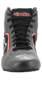 Scarpe Alpinestars Tech-1 K Start V2, scarpe da karting, Asphalt Black e Arancione Fluo, vista frontale che mostra lacci neri, marchio Alpinestars arancione sulla linguetta, logo a stella bianco sulla punta e pannelli in microfibra traforata