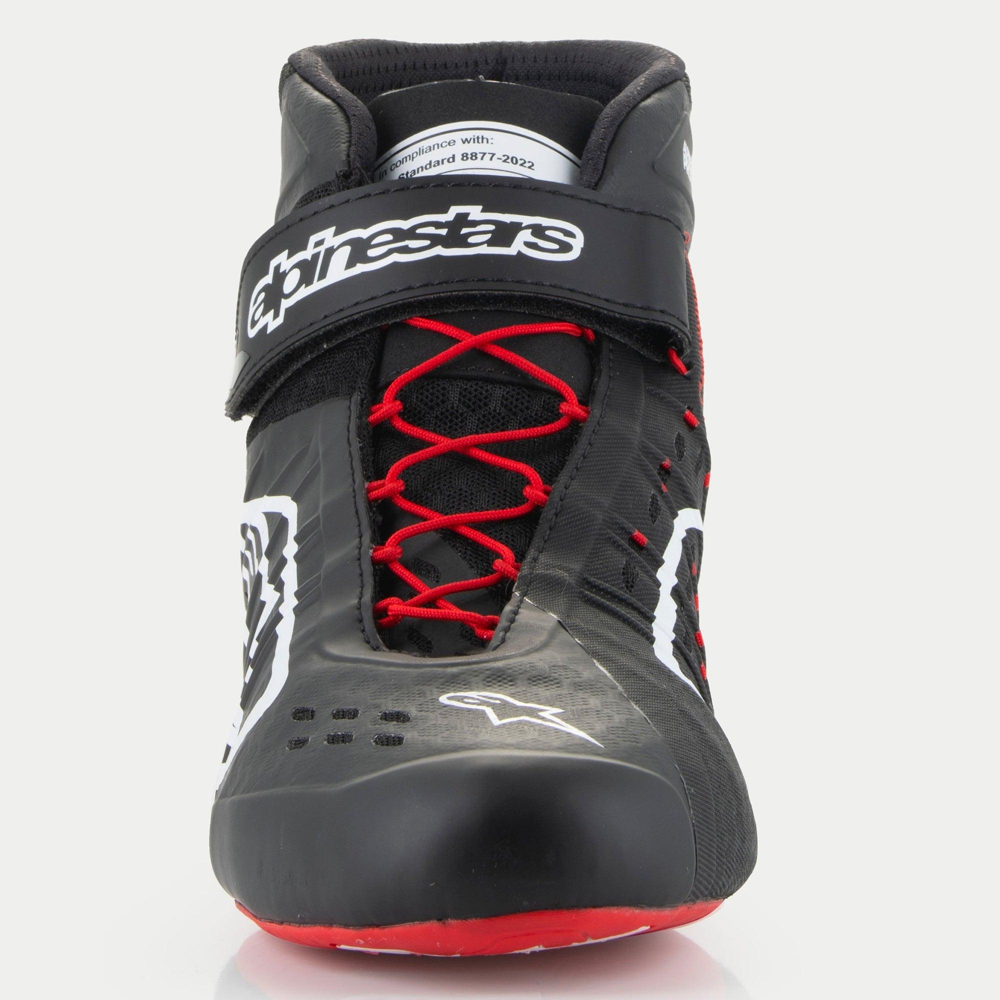 Scarpe Alpinestars Tech-1 KX V3, scarpe da kart, nero, bianco e rosso, vista frontale con allacciatura asimmetrica rossa, cinturino in Velcro nero alla caviglia con marchio bianco ed etichetta di certificazione FIA 8877-2022 sulla linguetta