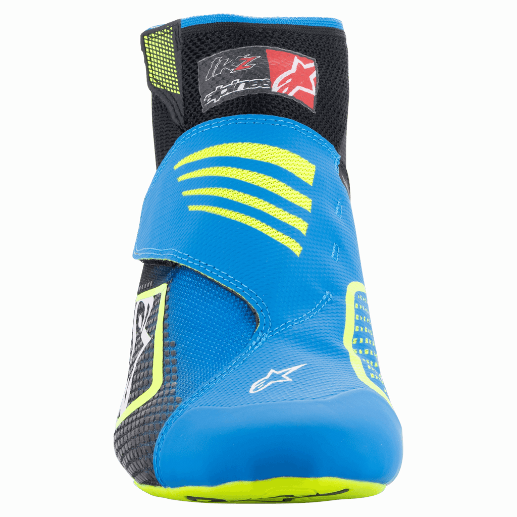 Scarpe Alpinestars Tech-1 KZ V2, scarpe da karting, nero, blu e giallo fluo, vista frontale che mostra la tomaia in maglia senza cuciture, cinturino blu vivace con dettagli gialli e colletto nero sulla caviglia