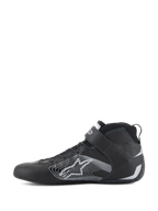 Alpinestars Tech-1 Z V3 Shoes FIA, scarpe da auto racing, nero e argento, vista laterale, tomaia in pelle bovina premium con un grande logo a stella stilizzato argento, cinturino alla caviglia in velcro e design high-top elegante per prestazioni motorsport professionali.