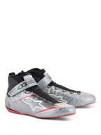 Alpinestars Scarpe Tech-1 Z V3 FIA, scarpe per corse automobilistiche, argento scuro con dettagli neri e rossi, tomaia in pelle argento metallizzato con sistema di allacciatura rapida nero, cinturino alla caviglia logato e suola sottile con dettagli rossi.