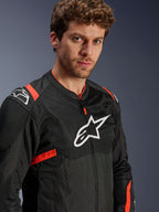 Giacca Alpinestars T-Sps Air V2, nero con accenti rosso fluo, giacca da moto in tessuto mesh, indossata da un modello, con logo Alpinestars bianco sul petto e sulle spalle, pannelli in mesh traspirante, stile urban sportivo