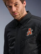 Giacca Alpinestars Ignite Air, nera, con colletto a camicia tradizionale e struttura in mesh traspirante, caratterizzata da una toppa con logo 'A' rosso e oro sul petto, indossata da un modello uomo, abbigliamento moto urbano