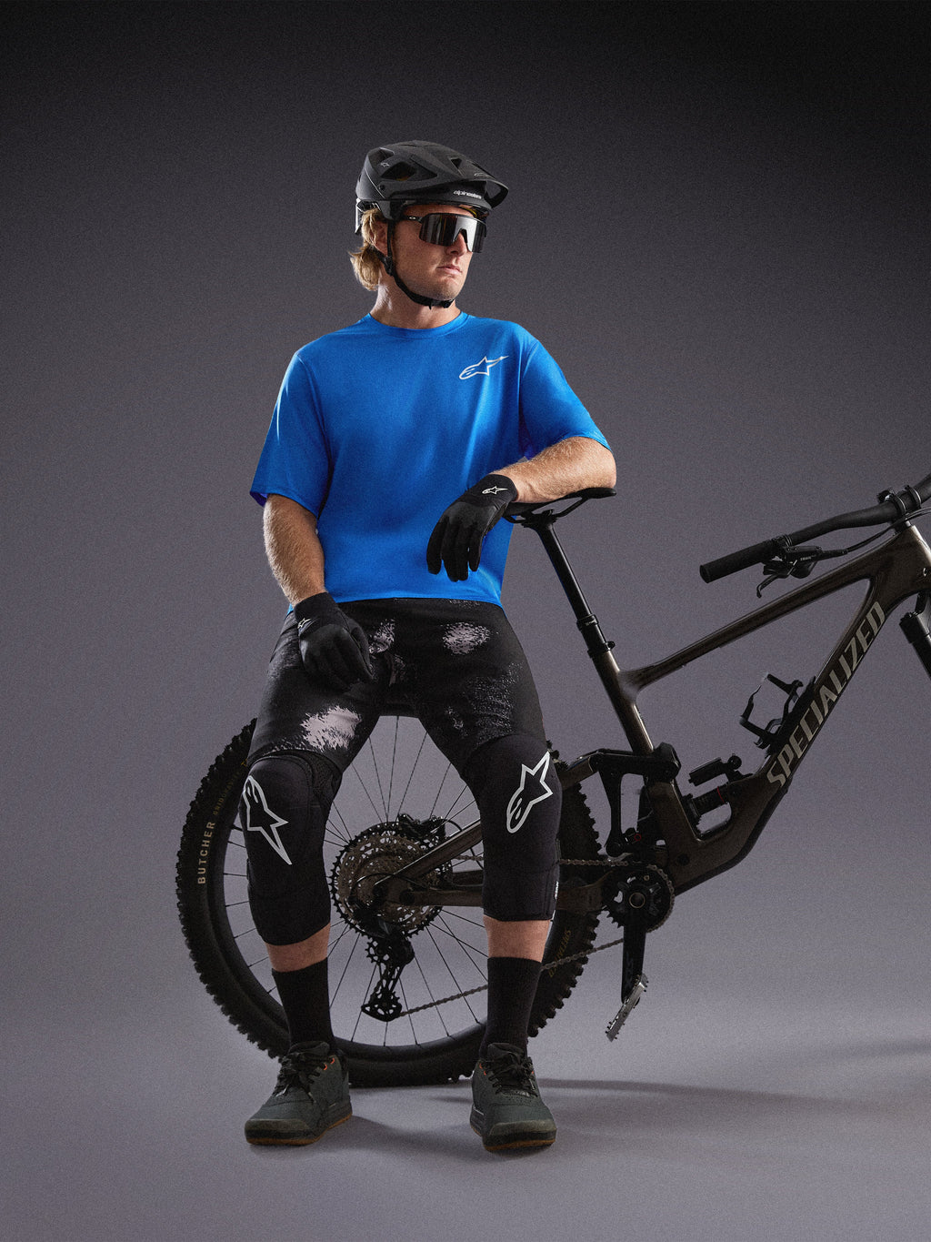 Maglia Alpinestars A-Dura Air SS blu e pantaloncini Ride Black Camo indossati da un ciclista con mountain bike.