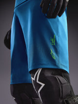 Alpinestars A-Dura Ride Shorts blu-verdi con loghi lime, abbinati a ginocchiere per il riding MTB.