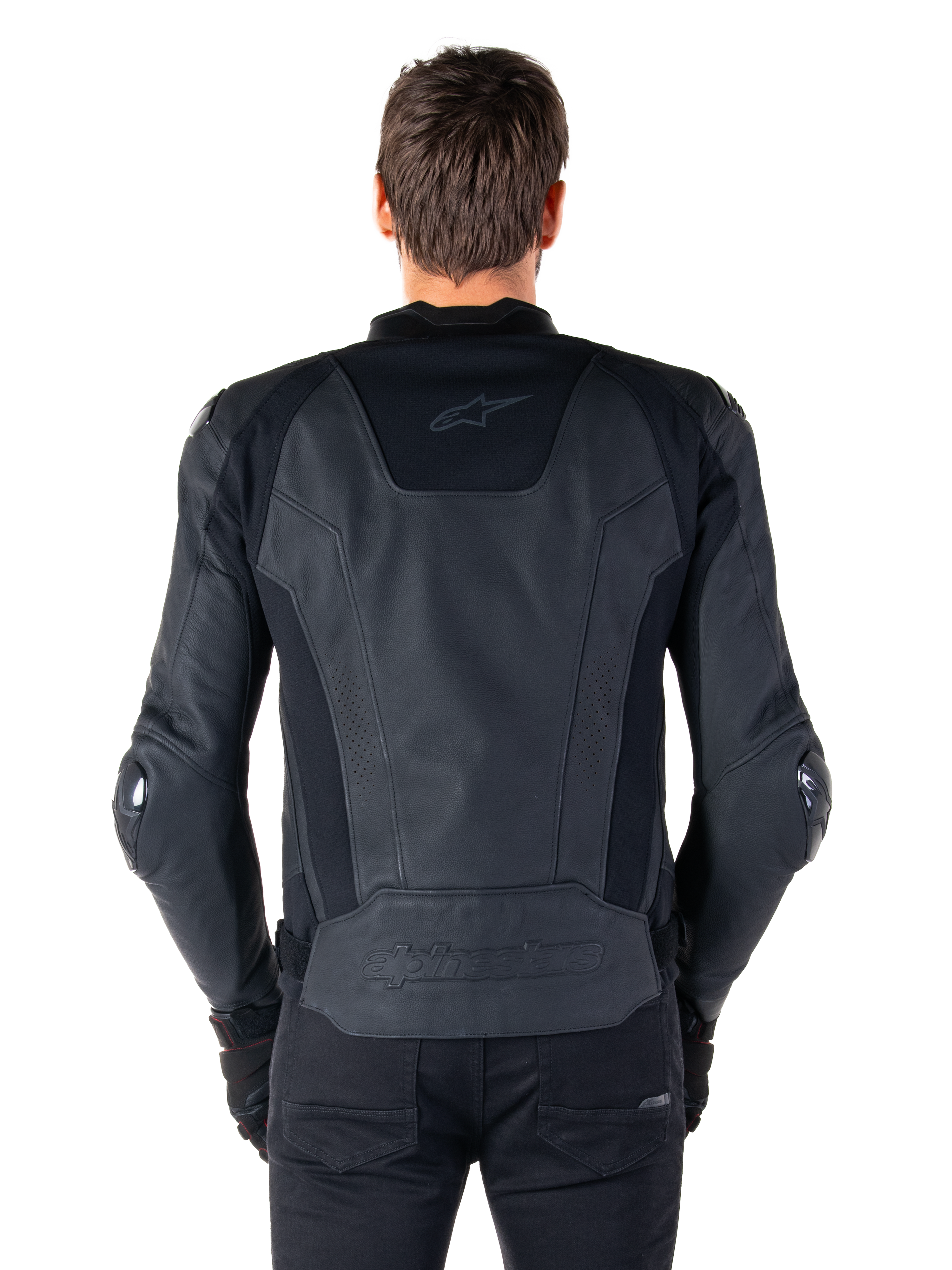 Vista posteriore di un pilota che indossa la giacca in pelle Alpinestars Missile V3 in nero, caratterizzata da una struttura in pelle pregiata con inserti tecnici elasticizzati, logo Alpinestars in rilievo sulla parte bassa della schiena e branding discreto sulla parte superiore, abbinata a pantaloni neri per un look sportivo da corsa coordinato.