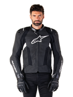 Giacca in pelle Alpinestars Missile V3, nera con loghi bianchi, indossata da un modello con guanti da moto neri, giacca da corsa in pelle premium con pannelli di ventilazione traforati e caratteristiche per prestazioni di guida
