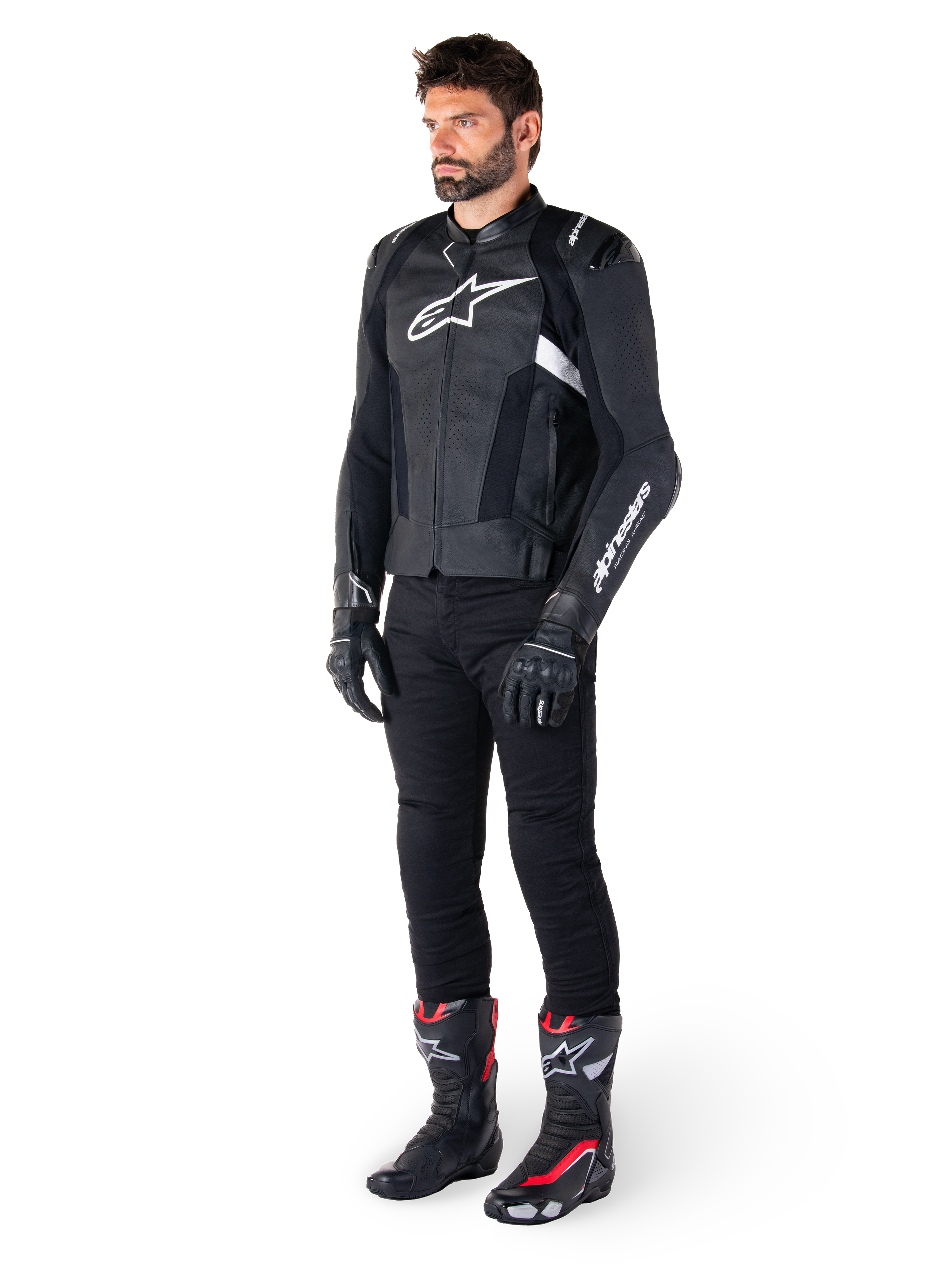 Pilota uomo che indossa la giacca in pelle Alpinestars Missile V3 in nero e bianco, con logo bianco sul petto e pannelli in pelle traforata, abbinata a pantaloni da moto neri, guanti neri e stivali da corsa neri e rossi per un look sportivo completo.