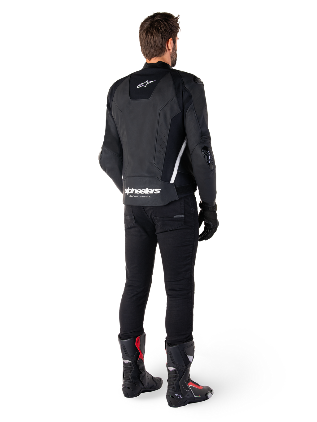 Giacca in pelle Alpinestars Missile V3, nera e bianca, vista posteriore sul pilota, con marchio Alpinestars bianco sulla parte inferiore della schiena e piccolo logo sulla parte superiore, indossata con pantaloni neri e stivali da corsa, costruzione in pelle premium per gare motociclistiche