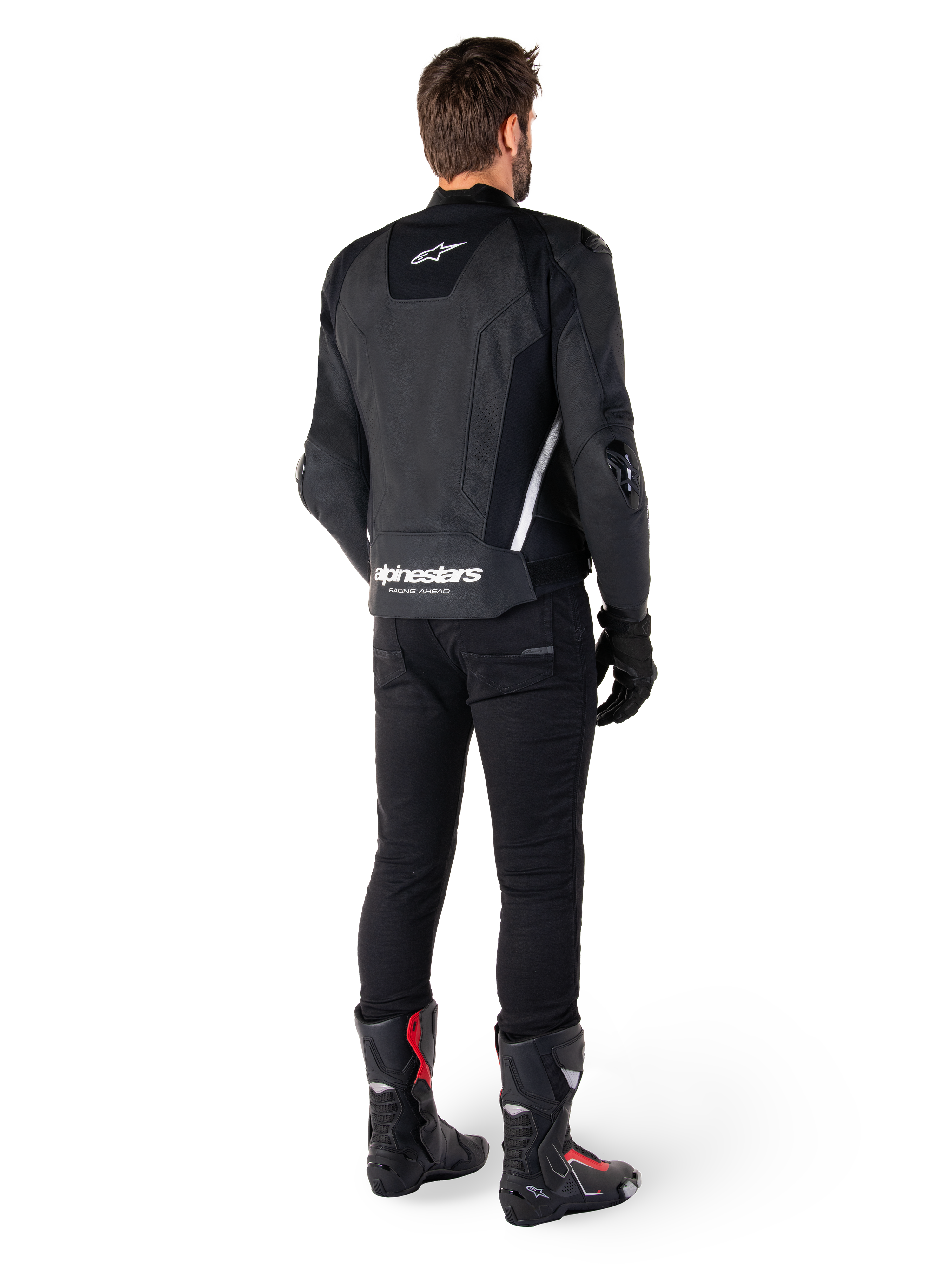 Giacca in pelle Alpinestars Missile V3, nera e bianca, vista posteriore sul pilota, con marchio Alpinestars bianco sulla parte inferiore della schiena e piccolo logo sulla parte superiore, indossata con pantaloni neri e stivali da corsa, costruzione in pelle premium per gare motociclistiche