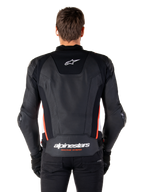 Giacca in pelle Alpinestars Missile V3, vista posteriore, in pregiata pelle nera con dettagli rosso fluo e bianchi, logo a stella bianco sulla parte superiore e scritta Alpinestars in basso, indossata con pantaloni e guanti neri