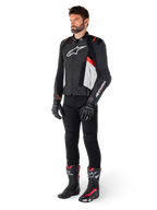 Modello che indossa la giacca in pelle Alpinestars Missile V3 in Nero Bianco e Rosso Fluo, abbinata a pantaloni, guanti e stivali da moto neri, con costruzione in pregiata pelle bovina e logo Alpinestars in evidenza, estetica sportiva professionale da corsa