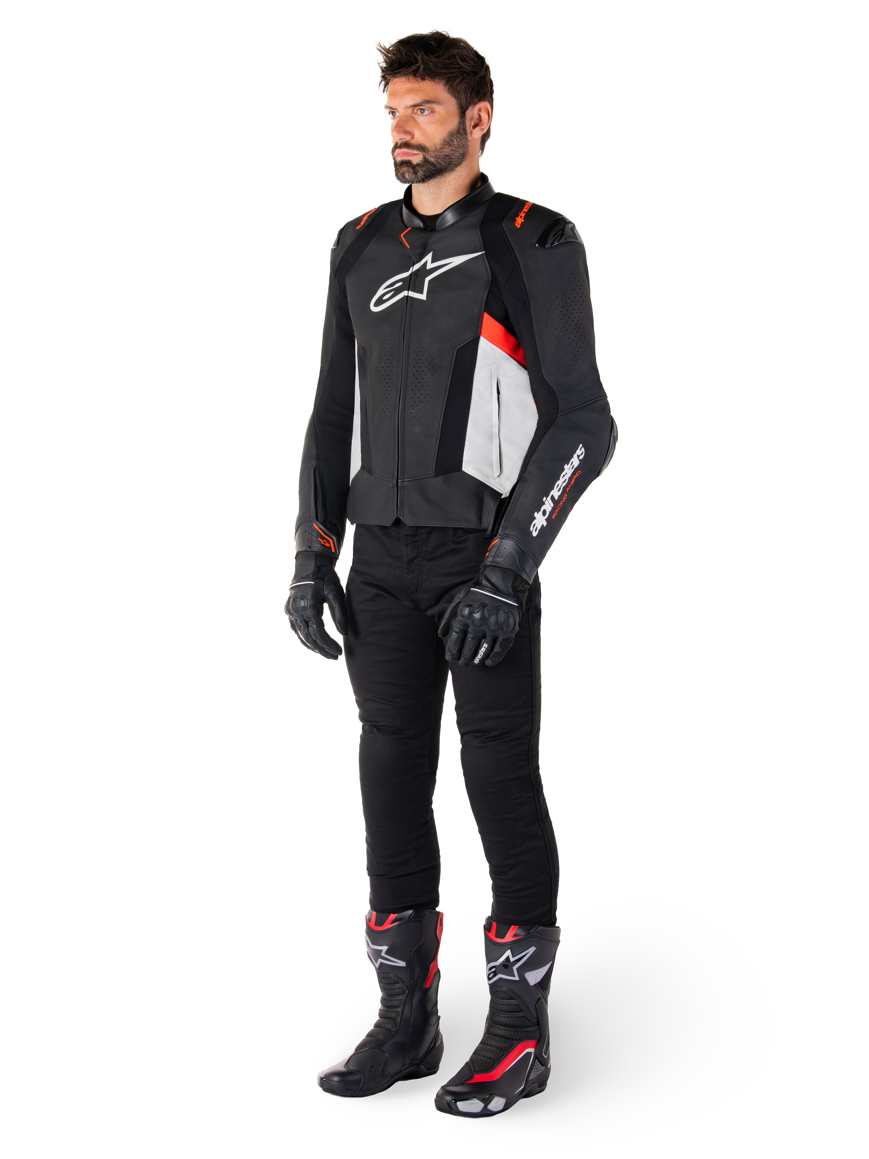 Modello che indossa la giacca in pelle Alpinestars Missile V3 in Nero Bianco e Rosso Fluo, abbinata a pantaloni, guanti e stivali da moto neri, con costruzione in pregiata pelle bovina e logo Alpinestars in evidenza, estetica sportiva professionale da corsa