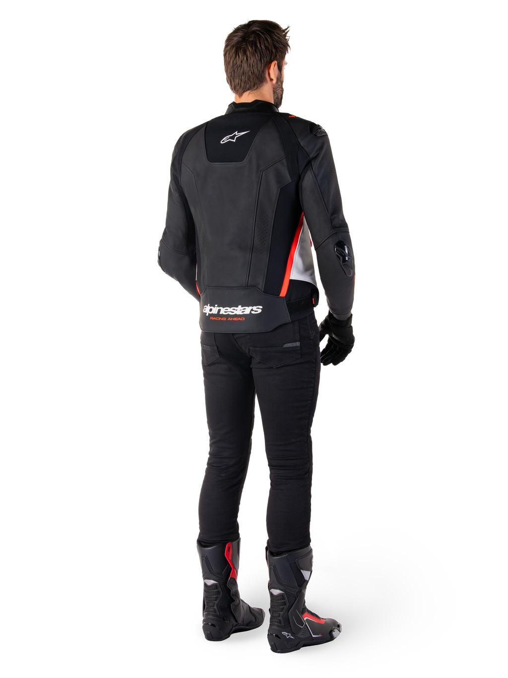 Alpinestars Missile V3 Leather Jacket in Nero Bianco Rosso Fluo, vista posteriore su un pilota uomo, con marchio Alpinestars sulla parte superiore e inferiore della schiena, abbinata a pantaloni neri e stivali da moto, giacca sportiva in pelle d'ispirazione racing.