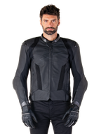 Giacca in pelle Alpinestars Missile V3 Airflow, nera, giacca da moto racing, indossata da un modello con guanti e pantaloni neri, con pannelli in pelle traforata, ventilazione in mesh e protezioni esterne sulle spalle, struttura in pelle premium per la guida sportiva.