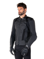 Giacca in pelle Alpinestars Missile V3 Airflow, Nero, indossata da un uomo con guanti e pantaloni da moto neri, con ampi pannelli in pelle traforata, protezioni per le spalle DFS e design sportivo race-fit.
