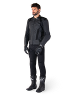 Alpinestars Missile V3 Airflow Leather Jacket, nero, indossata da un pilota con pantaloni, guanti e stivali neri coordinati, con pelle bovina traforata per la massima ventilazione e protezioni DFS sulle spalle, abbigliamento da moto sportivo premium