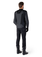 Vista posteriore di un uomo che indossa la giacca in pelle Alpinestars Missile V3 Airflow in nero, dotata di ampi pannelli traforati per la ventilazione, abbinata a pantaloni da moto e stivali neri, che mette in mostra un'estetica racing aerodinamica.