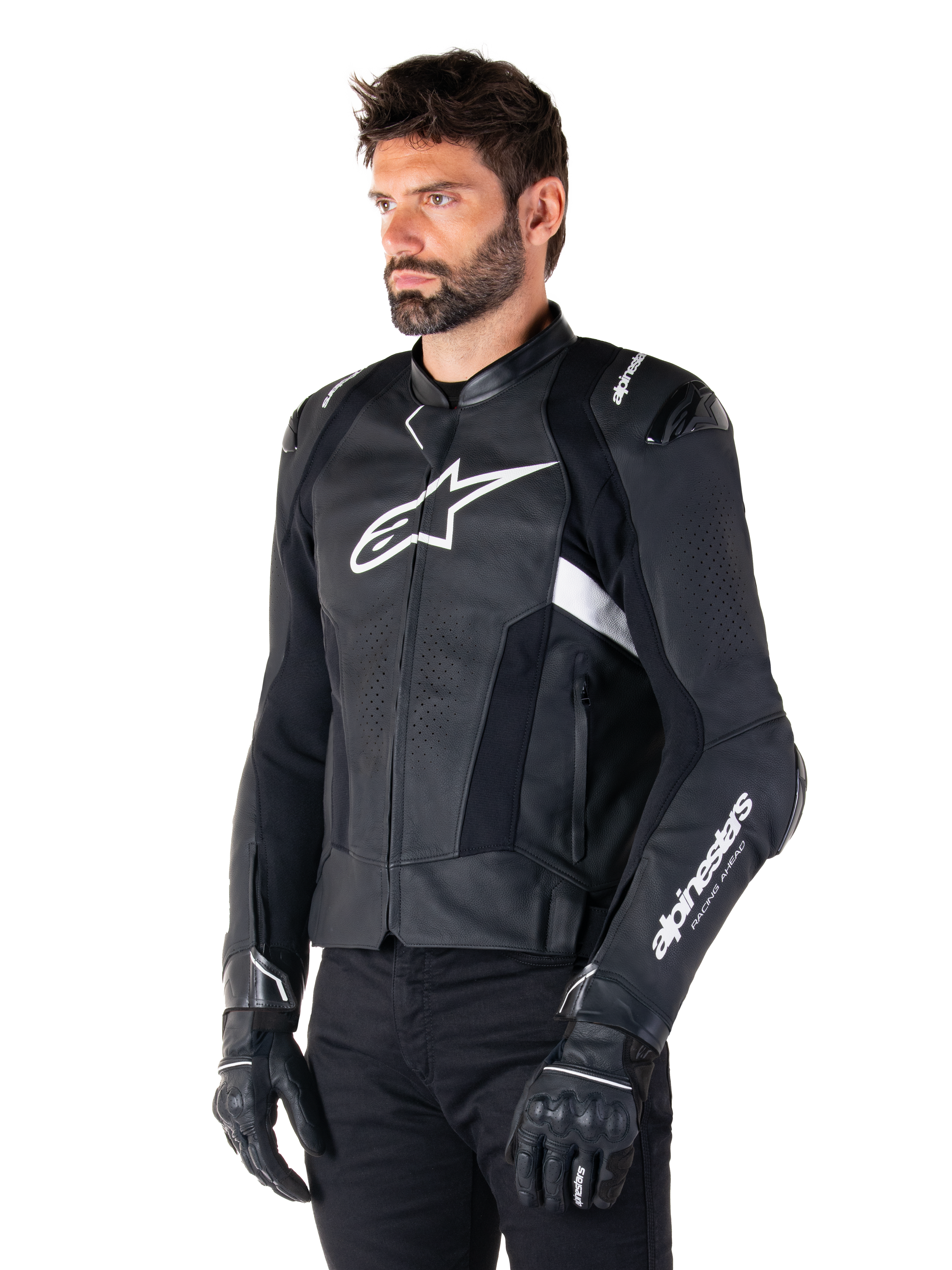 Uomo che indossa la giacca in pelle Alpinestars Missile V3 Airflow, giacca da moto in nero e bianco, pelle pregiata traforata per il flusso d'aria, logo Alpinestars bianco su petto e manica, vestibilità sportiva ispirata alle corse, indossata con guanti e pantaloni neri.