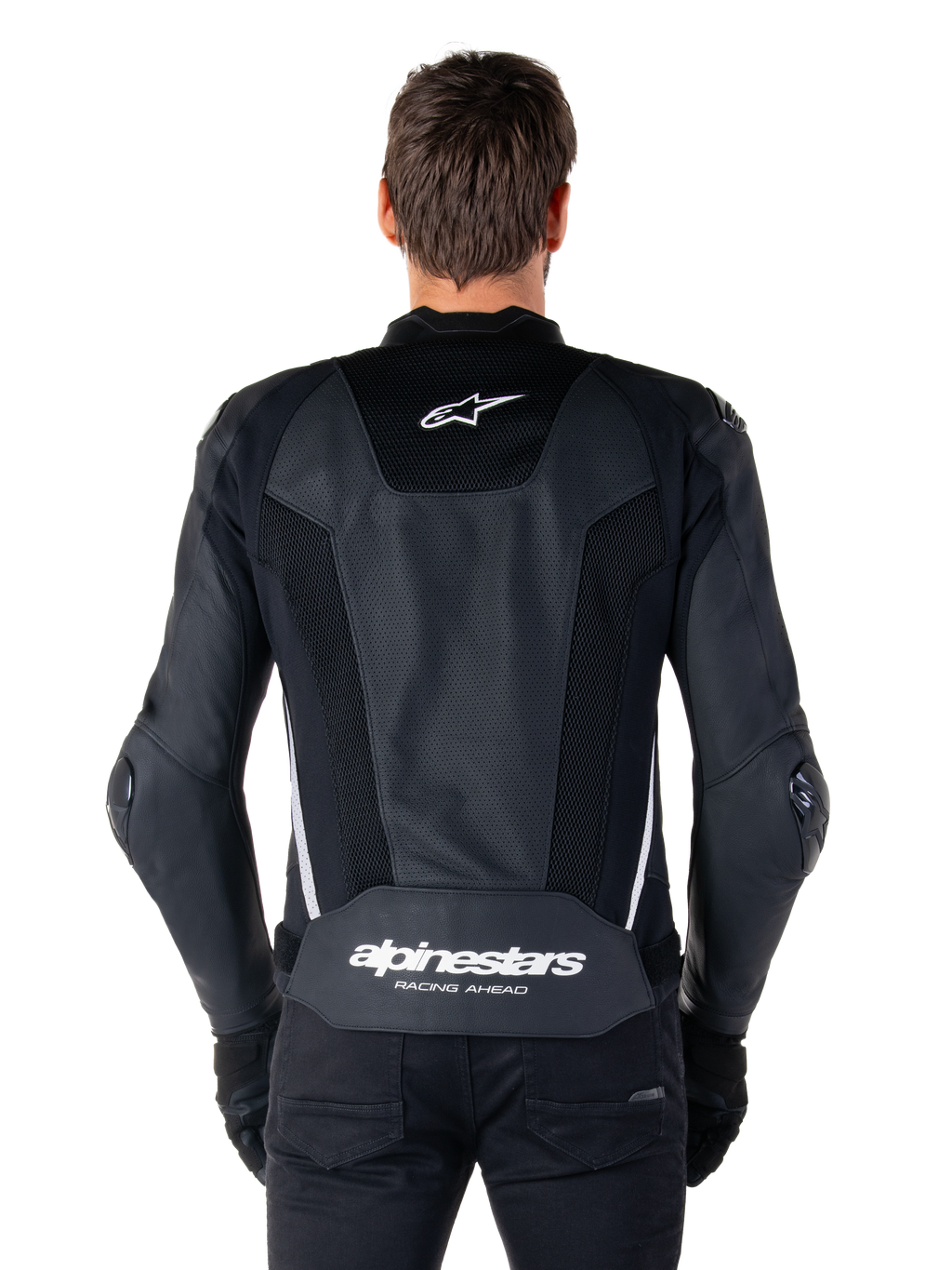 Giacca in pelle Alpinestars Missile V3 Airflow, nero e bianco, vista posteriore indossata da un pilota, con ampi pannelli in pelle traforata, accenti laterali bianchi, logo a stella Alpinestars sulla parte superiore della schiena e marchio 'alpinestars RACING AHEAD' sulla parte inferiore della schiena.