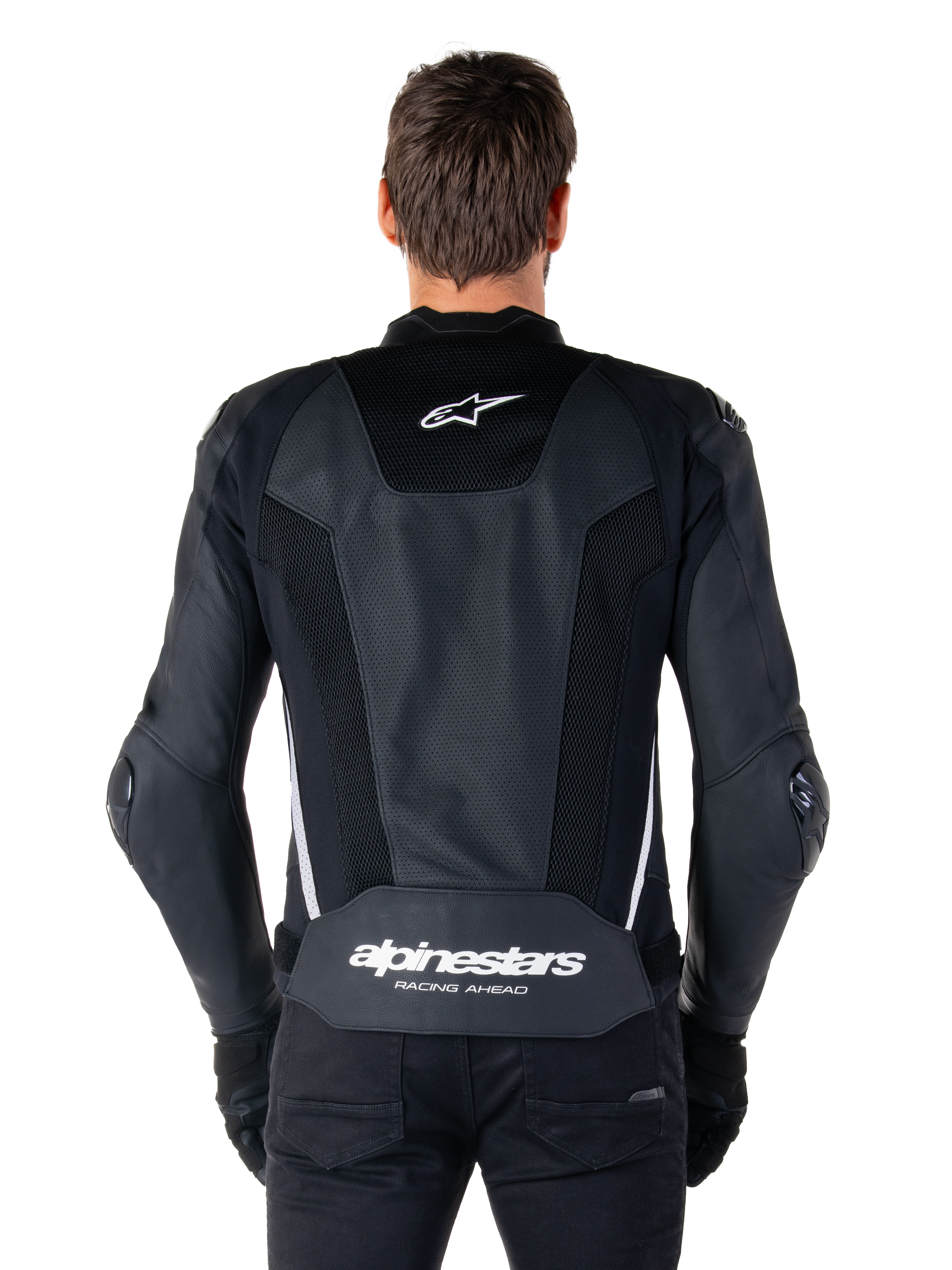 Giacca in pelle Alpinestars Missile V3 Airflow, nero e bianco, vista posteriore indossata da un pilota, con ampi pannelli in pelle traforata, accenti laterali bianchi, logo a stella Alpinestars sulla parte superiore della schiena e marchio 'alpinestars RACING AHEAD' sulla parte inferiore della schiena.