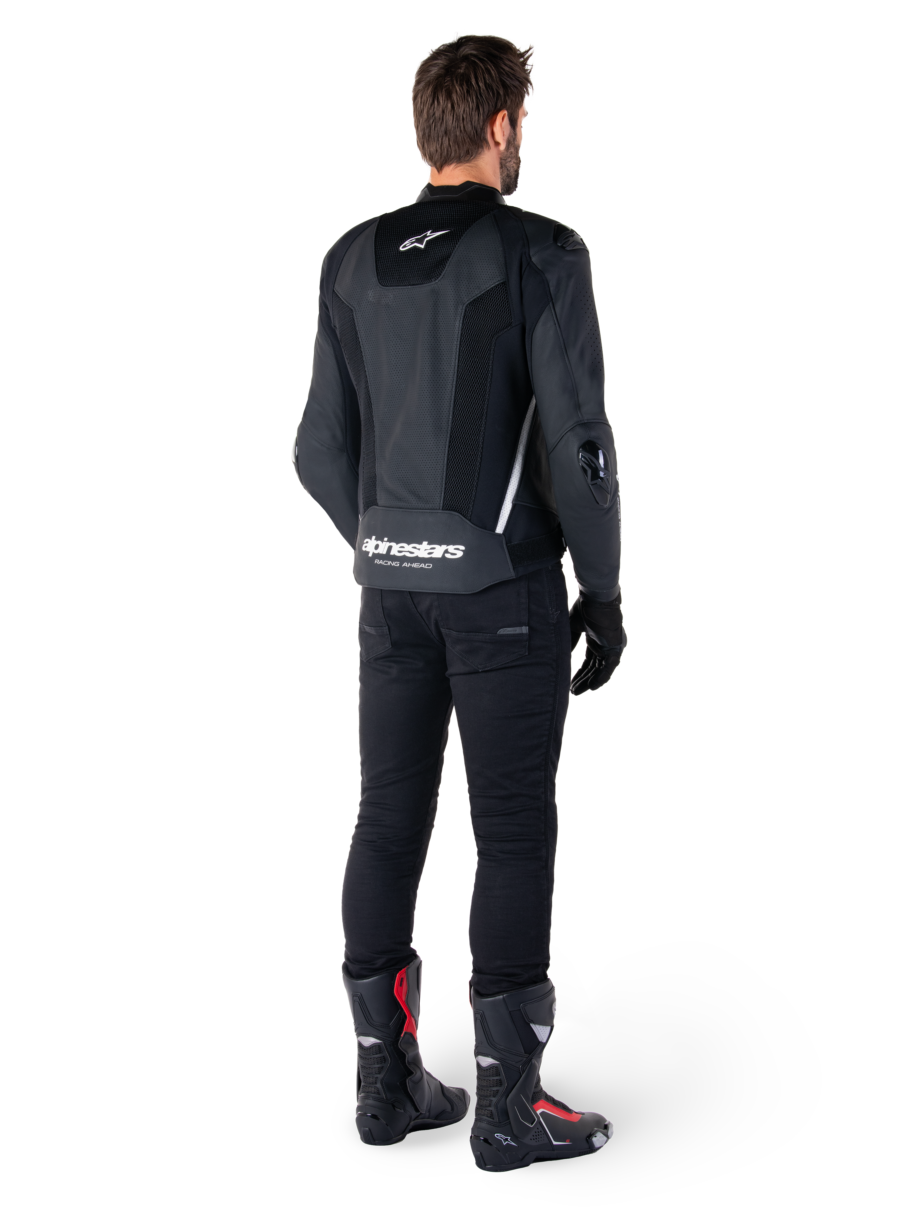 Alpinestars Missile V3 Airflow Leather Jacket, nero e bianco, vista posteriore indossata con pantaloni tecnici neri e stivali da corsa, caratterizzata da pannelli posteriori in pelle traforata e logo Alpinestars sulla parte bassa della schiena.