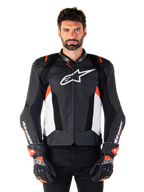 Giacca Alpinestars Missile V3 Airflow in pelle, giacca da moto racing, nero e bianco con accenti rosso fluo, pannelli di ventilazione traforati, logo stella bianco sul petto, indossata con guanti neri e rossi, costruzione in pelle pregiata