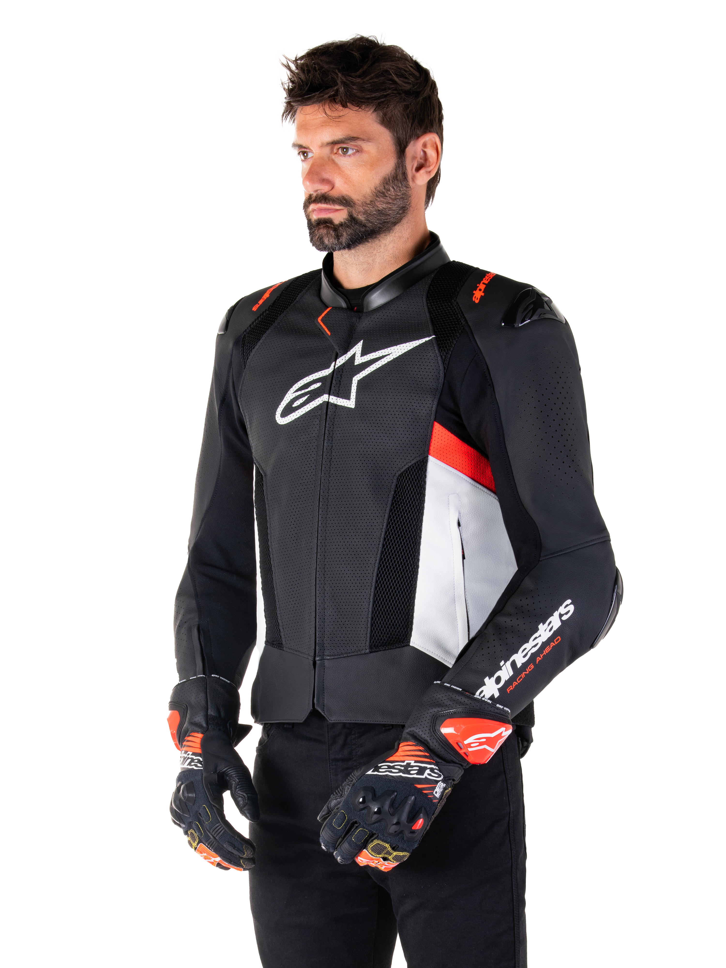 Alpinestars Missile V3 Airflow Leather Jacket, giacca da moto sportiva racing, nero bianco e rosso fluo, indossata da un modello con guanti coordinati, caratterizzata da pannelli in pelle traforata, grande logo bianco sul petto e slider sulle spalle neri.