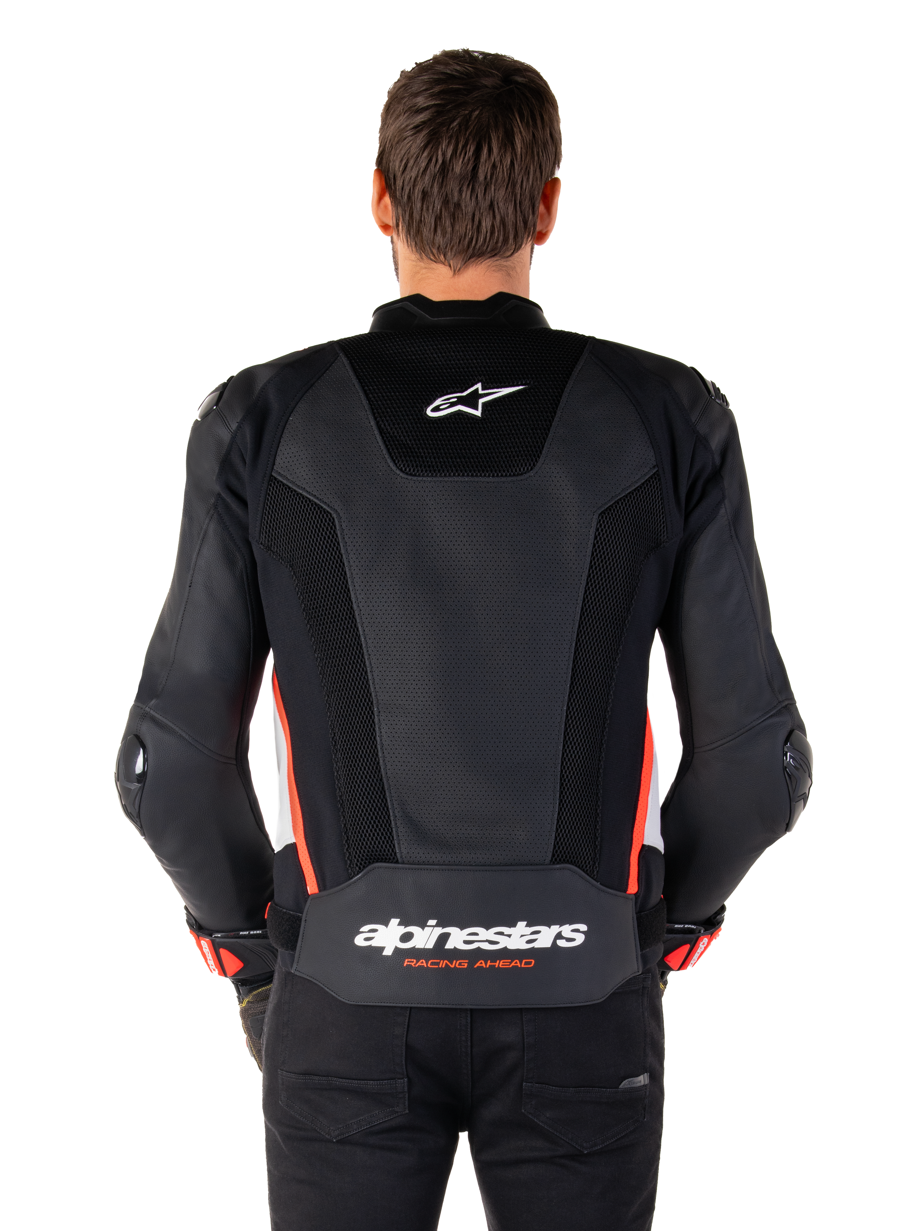Vista posteriore di una persona che indossa la giacca in pelle Alpinestars Missile V3 Airflow in Nero Bianco Rosso Fluo, caratterizzata da ampi pannelli in pelle traforata per la ventilazione, un piccolo logo Alpinestars sulla parte superiore della schiena e il marchio 'alpinestars RACING AHEAD' sulla parte inferiore della vita.