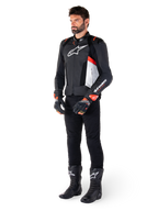 Giacca in pelle Alpinestars Missile V3 Airflow, nero bianco rosso fluo, indossata da un modello con pantaloni neri, guanti da corsa neri e stivali neri, caratterizzata da pelle traforata per la ventilazione, logo bianco sul petto e accenti rosso fluo, progettata per prestazioni racing e sportive di alto livello.