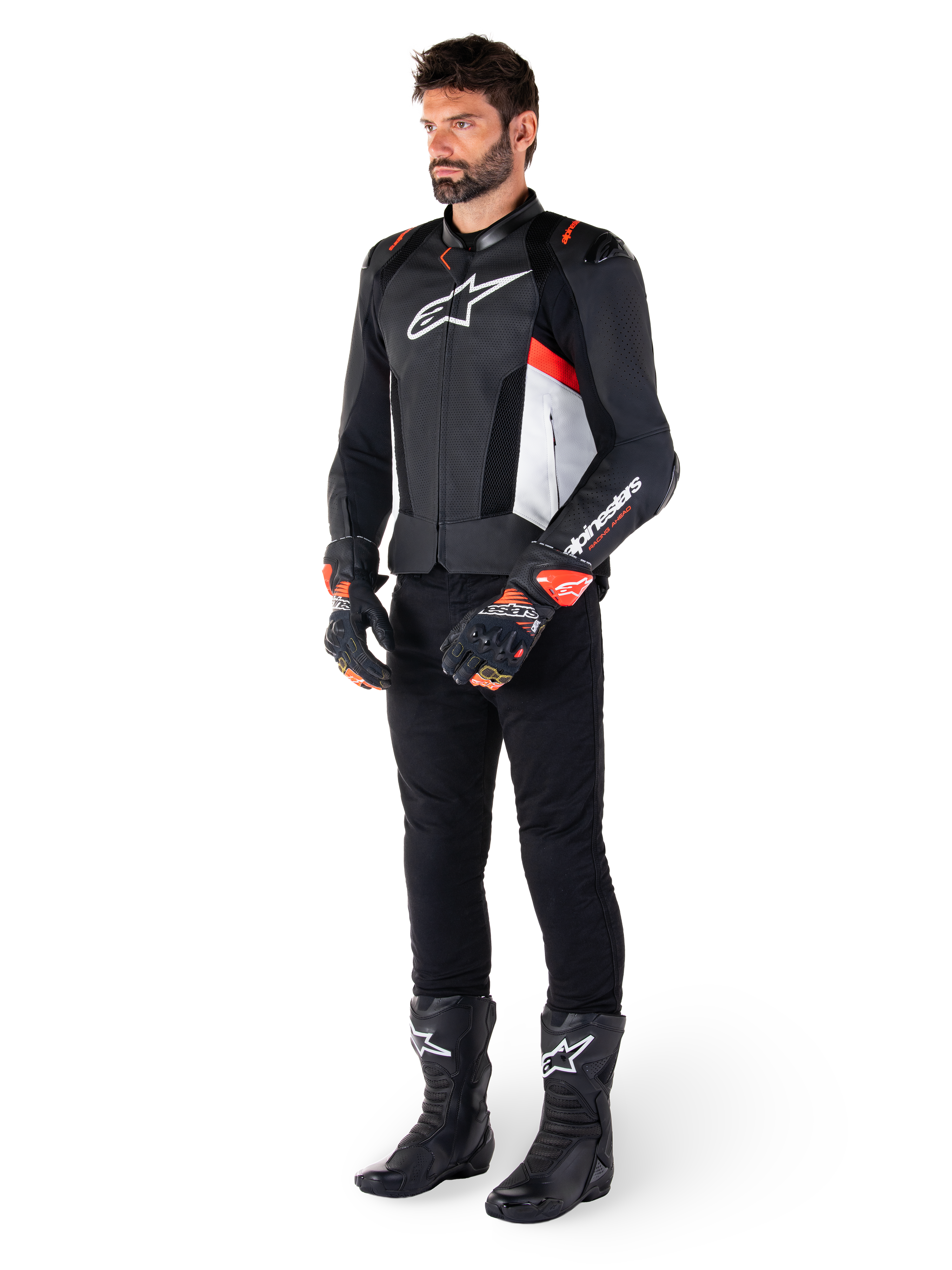 Giacca in pelle Alpinestars Missile V3 Airflow, nero bianco rosso fluo, indossata da un modello con pantaloni neri, guanti da corsa neri e stivali neri, caratterizzata da pelle traforata per la ventilazione, logo bianco sul petto e accenti rosso fluo, progettata per prestazioni racing e sportive di alto livello.