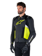 Modello uomo che indossa la giacca in pelle Alpinestars Missile V3 Airflow, nero con dettagli giallo fluo e bianchi, caratterizzata da pelle traforata per la massima ventilazione, vistoso logo giallo sul petto, abbinata a guanti e pantaloni neri, abbigliamento da moto sportivo da corsa