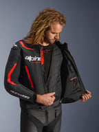 Giacca in pelle Alpinestars GP Force V2 in nero e rosso fluo, vista interna dettagliata su modello che mostra il gilet termico rimovibile e la tasca interna impermeabile, costruzione in pelle premium per la protezione nella guida sportiva.