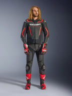 Modello uomo che indossa la giacca in pelle Alpinestars GP Force V2 in nero e rosso fluo, abbinata a pantaloni in pelle coordinati, guanti racing rossi e stivali performance rossi, abbigliamento sportivo da moto professionale