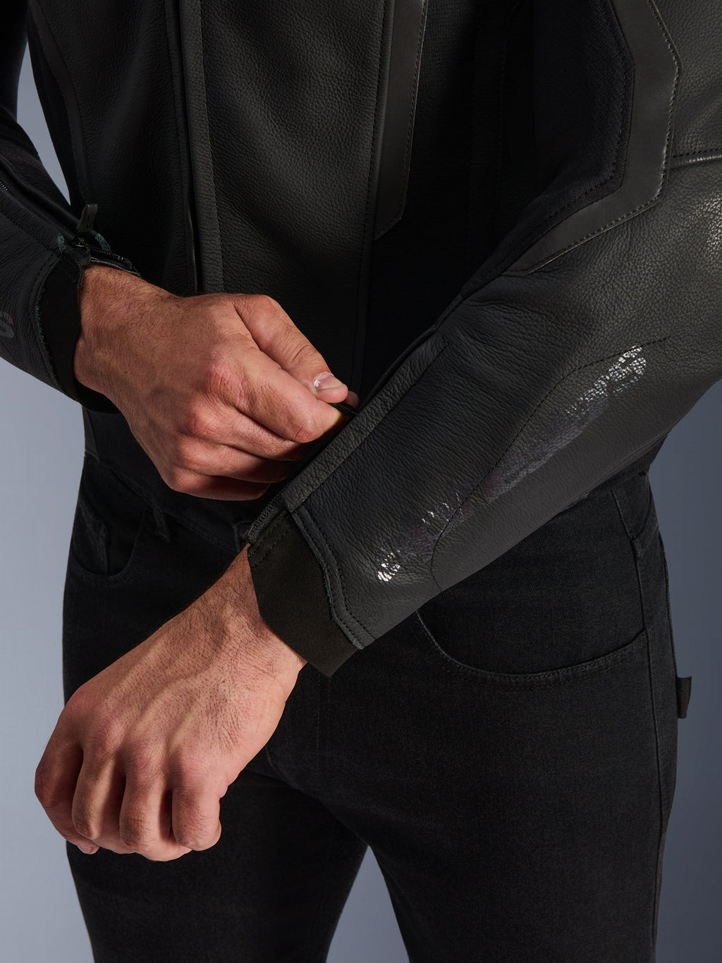 Giacca in pelle Alpinestars GP Force V2, nero, vista ravvicinata del polsino ergonomico, persona che regola la chiusura del polso, costruzione in pelle bovina premium con dettagli tecnici per la guida sportiva in moto