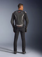 Giacca in pelle Alpinestars GP Force V2, nero e bianco, vista posteriore, indossata da un pilota con pantaloni e guanti neri, con grande logo bianco sulla parte bassa della schiena e dettagli rossi, realizzata in pregiata pelle bovina per abbigliamento moto stradale